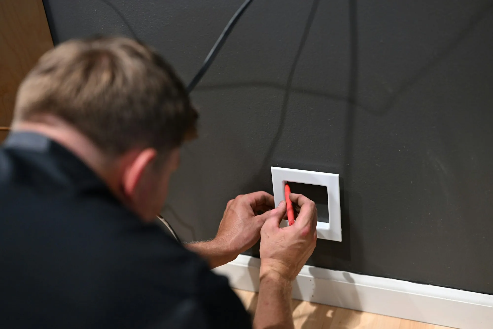 Electrician fitting a switch plate to a wall